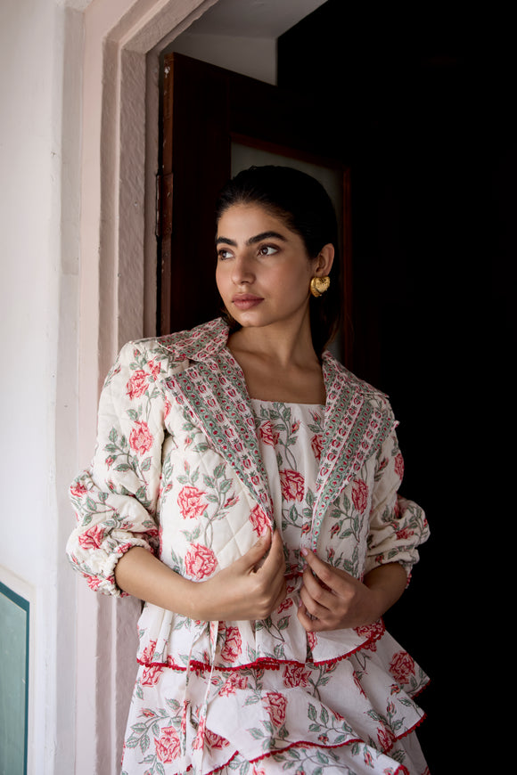 Woman wearing a floral dress with a matching jacket indoors.