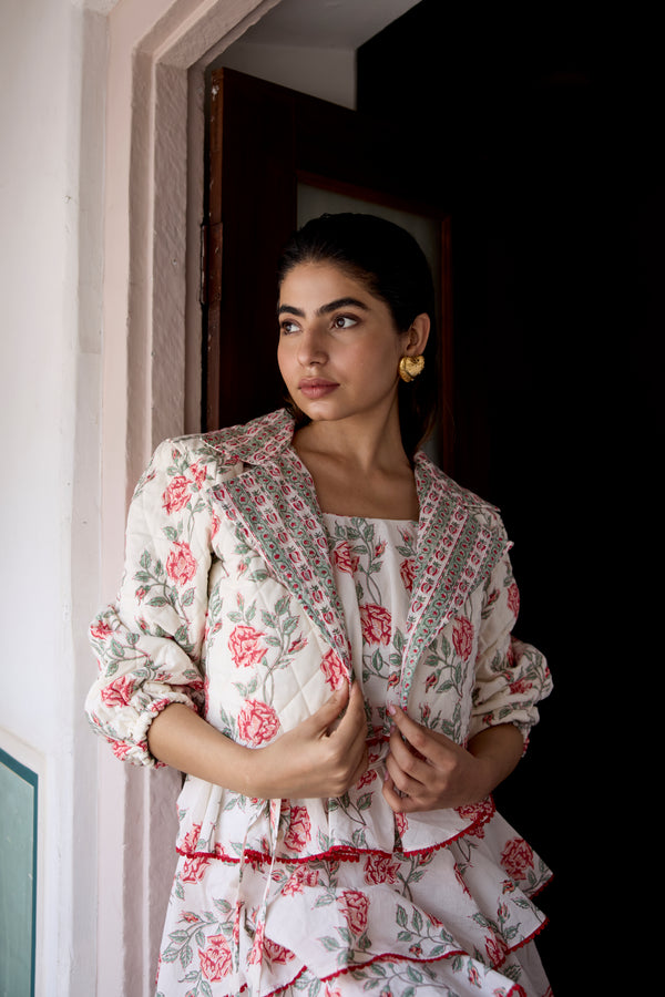 Woman wearing a floral dress with a matching jacket indoors.